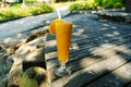 a glass of orange juice on the sandy beach. Fresh orange juice, fruits on sand with wooden background, summer concept Royalty Free Stock Photo