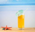 Glass of orange juice on the sea and sandy beach near starfish Royalty Free Stock Photo