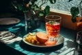 a glass of orange juice sits on a table next to a plate of fruit