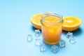 Glass of orange juice with sliced orange fruit and ice cubes on blue Royalty Free Stock Photo