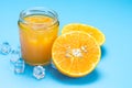 Glass of orange juice with sliced orange fruit and ice cubes on blue Royalty Free Stock Photo