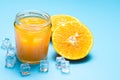 Glass of orange juice with sliced orange fruit and ice cubes on blue Royalty Free Stock Photo