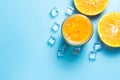 Glass of orange juice with sliced orange fruits with ice cubes on blue background