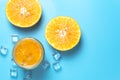 Glass of orange juice with sliced orange fruits with ice cubes on blue background Royalty Free Stock Photo