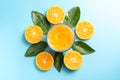 Glass of orange juice with sliced orange fruits with leaves on blue background