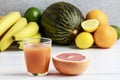 Glass of orange juice and stack of various fruits