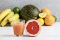 Glass of orange juice and stack of various fruits