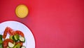 Glass with orange juice and white plate with fresh salad on bright background Royalty Free Stock Photo