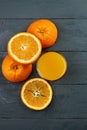 Glass of orange juice on wooden table with fresh sliced fruits of orange.