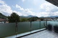 A glass parapet of a modern building balcony overlooking hills