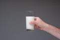 Glass of pasteurised milk hand by Caucasian male hand. Close up studio shot,  on gray Royalty Free Stock Photo