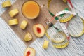 A glass of peach juice on a sackcloth on a white wooden table with slices of fruit and a fork and a centimeter Royalty Free Stock Photo