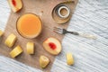 A glass of peach juice on a sackcloth on a white wooden table with slices of fruit and a fork and a centimeter Royalty Free Stock Photo