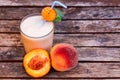 Glass of peach yoghurt and peaches on wooden table Royalty Free Stock Photo