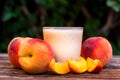 Glass of peach yoghurt and peaches on wooden table Royalty Free Stock Photo