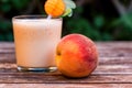 Glass of peach yoghurt and peaches on wooden table Royalty Free Stock Photo