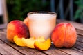 Glass of peach yoghurt and peaches on wooden table Royalty Free Stock Photo