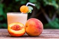 Glass of peach yoghurt and peaches on wooden table Royalty Free Stock Photo