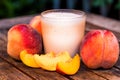 Glass of peach yoghurt and peaches on wooden table Royalty Free Stock Photo