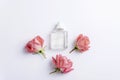 Glass perfume bottle and coral pink rose flowers on white background. Top view, flat lay, mockup Royalty Free Stock Photo