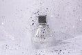 Glass perfume bottle with silver sequins on light background Royalty Free Stock Photo