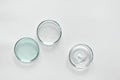 Glass petri dish with different cosmetic products on white background. Shampoo, hair conditioner or mask and shower gel