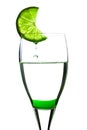 A glass with a piece of lime and drops