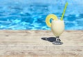 Glass of pinacolada cocktail standing on the swimming pool ledge