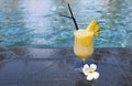 Glass of pinacolada cocktail standing on the swimming pool ledge