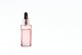 Glass pink bottle with a pipette with face serum on a white background