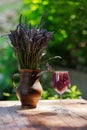 Glass of pink cocktail and bouquet of lavender on wooden table against greenery Royalty Free Stock Photo