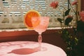 a glass of pink drink with an orange slice on it