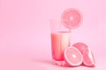 A glass with pink orange juice with the cut oranges on a pink background. Juicy color scale, pin up, pop up styles. Food for break Royalty Free Stock Photo