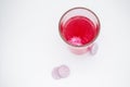 In a glass with pink water, a soluble, instant or dissolve pink tablet bubbles. Nearby are similar tablets: vitamin C, dietary Royalty Free Stock Photo