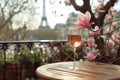 Glass of pink wine on a table of typical Parisian outdoor cafe with pink magnolia flowers in full bloom on a backdrop of French