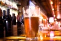 Glass Pint of amber beer with colorful blur of bar