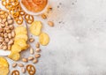 Glass pint of craft lager beer with snack on stone kitchen table background. Pretzel and crisps and pistachio on roud wooden board Royalty Free Stock Photo