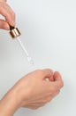 A glass pipette in a woman`s hand drips essential oil onto her hand. Cosmetic procedures Royalty Free Stock Photo