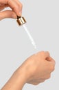 A glass pipette in a woman's hand drips essential oil onto her hand Royalty Free Stock Photo