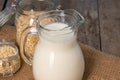Glass pitcher of milk and oat flakes on wooden table Royalty Free Stock Photo
