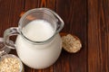 Glass pitcher of milk and oat flakes on wooden table Royalty Free Stock Photo