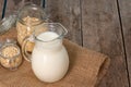 Glass pitcher of milk and oat flakes on wooden table Royalty Free Stock Photo