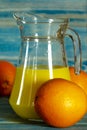 Glass and pitcher of orange juice on wooden table, on green background Royalty Free Stock Photo