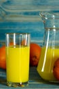 Glass and pitcher of orange juice on wooden table, on green background Royalty Free Stock Photo