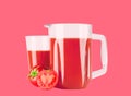 Glass pitcher with tomato juice on pastel pink background