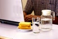 Glass and pitcher of water and a stack of crackers and man working on a laptop computer in the background Royalty Free Stock Photo