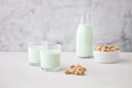 A glass of plant-based nut milk is on the table next to a bottle of pistachio milk and pistachios. The perfect drink for