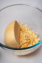 Glass plate with grated cheese and a piece of cheese on a white table