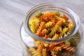 A glass pot, jar or bowl full of spirelli in three different colors. The uncooked tricolore italian pasta variant is orange, Royalty Free Stock Photo
