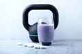 Glass of Protein Shake with milk and blueberries. Creatine capsules and black sporting kettlebell in background. Sport nutrition. Royalty Free Stock Photo